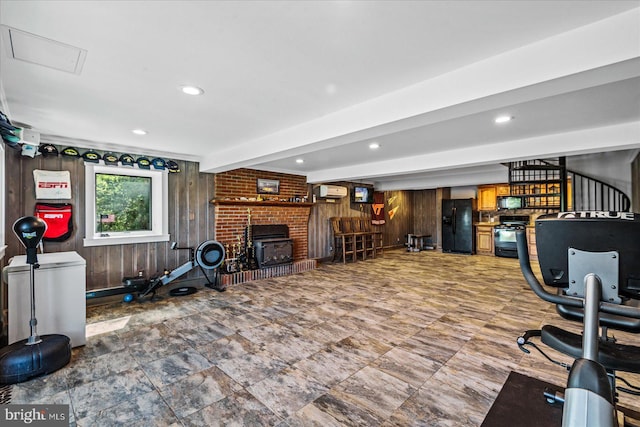 exercise room featuring a fireplace, wood walls, and recessed lighting