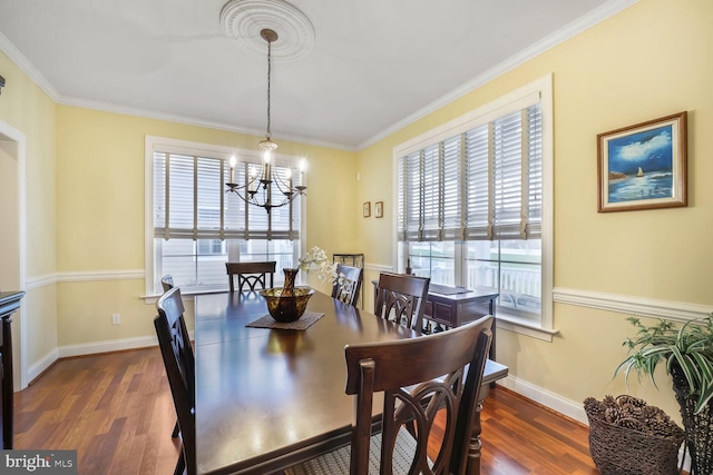 dining room featuring dark wood-type flooring, ornamental molding, baseboards, and a notable chandelier
