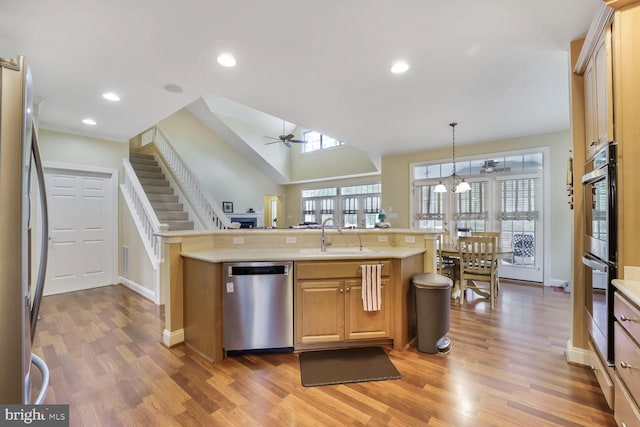kitchen featuring light countertops, appliances with stainless steel finishes, ceiling fan, and light wood finished floors