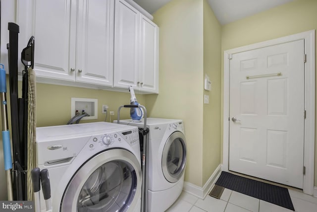 laundry room with light tile patterned floors, baseboards, cabinet space, and washer and clothes dryer