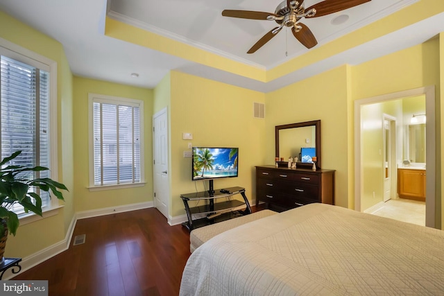 bedroom with visible vents, baseboards, wood finished floors, and a raised ceiling