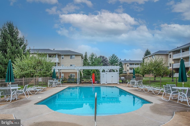 community pool featuring a pergola, a patio area, and fence