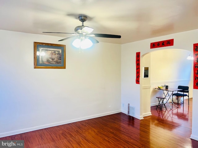 unfurnished room featuring visible vents, baseboards, arched walkways, a ceiling fan, and wood finished floors