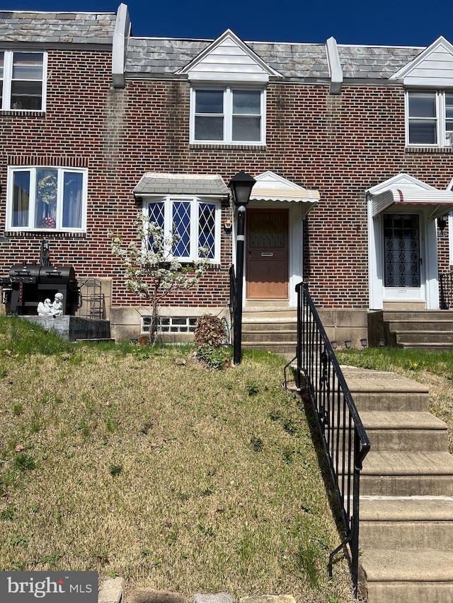 multi unit property with a front yard, brick siding, and entry steps
