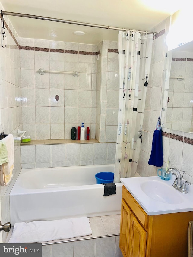 bathroom with shower / bath combo, tile patterned floors, vanity, and tile walls