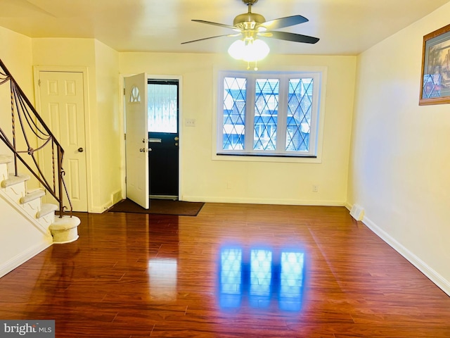 foyer entrance with stairs, ceiling fan, baseboards, and wood finished floors