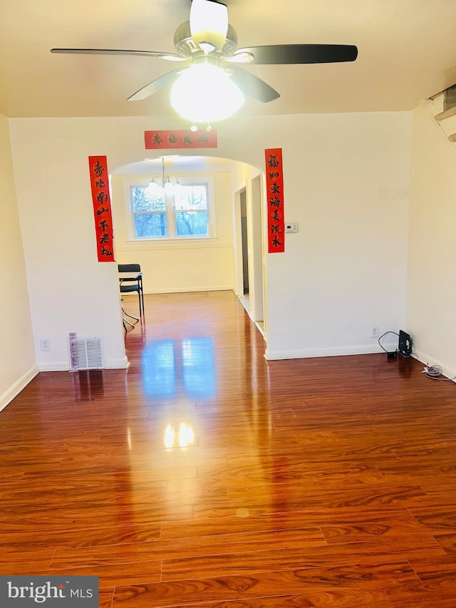 spare room with arched walkways, wood finished floors, a ceiling fan, and visible vents