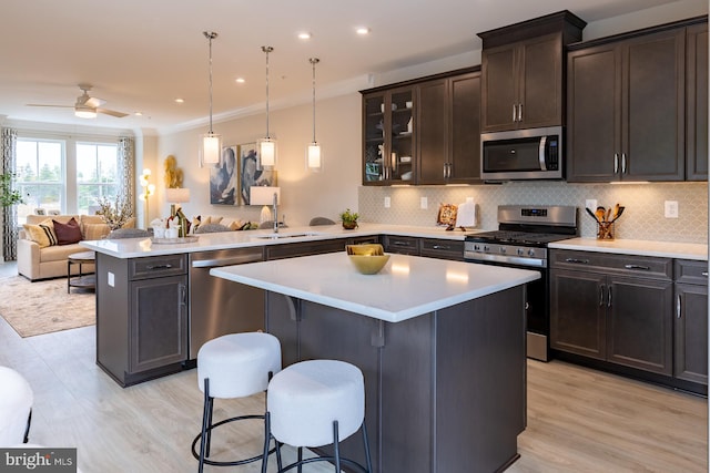 kitchen featuring a peninsula, tasteful backsplash, a sink, stainless steel appliances, and open floor plan