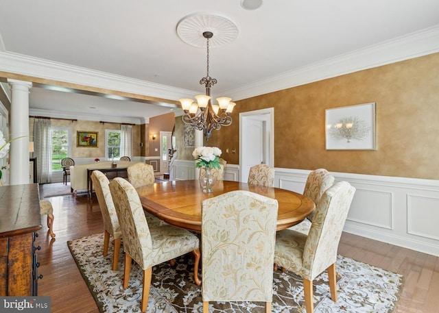 dining area featuring wainscoting, wood finished floors, a chandelier, and ornamental molding