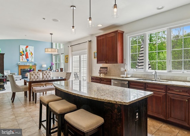 kitchen with hanging light fixtures, a sink, light tile patterned floors, dishwasher, and a kitchen island