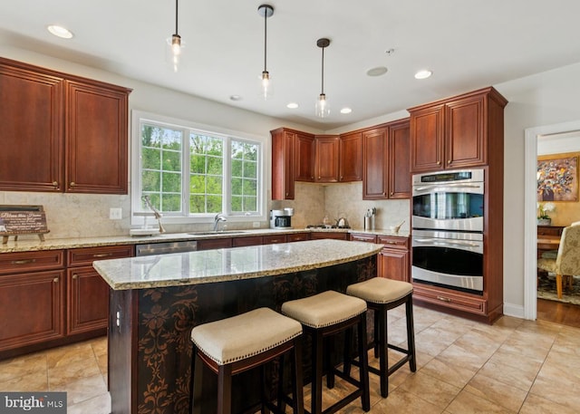 kitchen featuring decorative light fixtures, decorative backsplash, appliances with stainless steel finishes, and a sink
