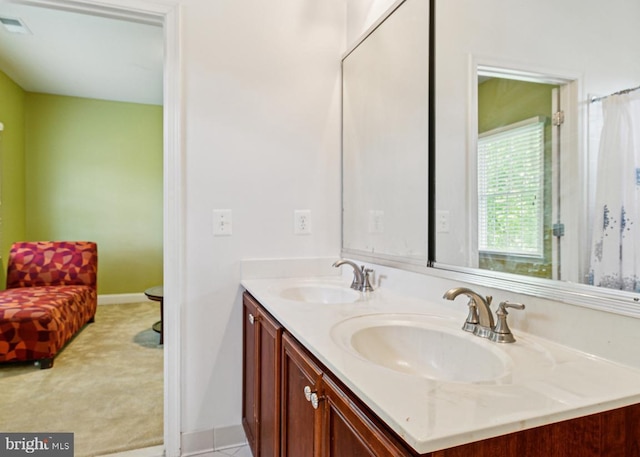 full bath with baseboards, visible vents, a sink, and double vanity