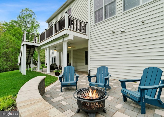 view of patio with stairway, ceiling fan, an outdoor fire pit, and a balcony