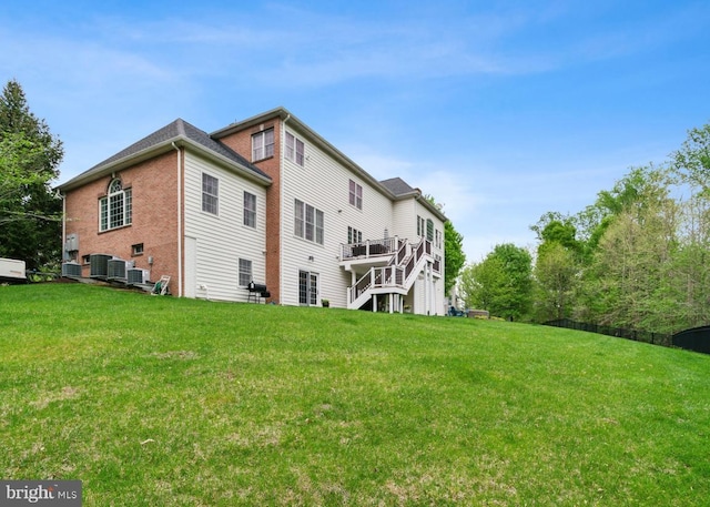 rear view of property featuring a wooden deck, a lawn, and central AC
