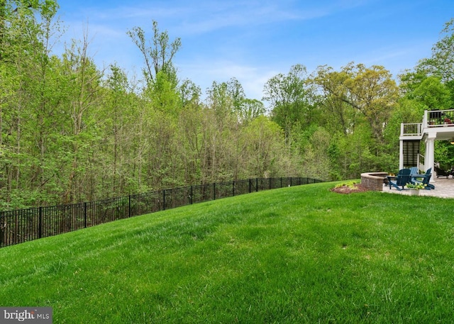 view of yard with a patio area, a view of trees, an outdoor fire pit, and fence