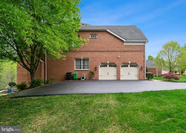 view of side of property featuring brick siding, aphalt driveway, a yard, and a garage