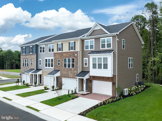 townhome / multi-family property with a garage, a front yard, a standing seam roof, driveway, and metal roof