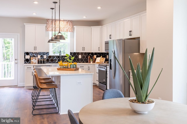 kitchen featuring decorative backsplash, white cabinets, appliances with stainless steel finishes, and a kitchen island