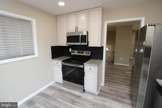 2214 Wintergreen Ave, District Heights, MD 20747 - kitchen with white cabinets, light wood-type flooring, appliances with stainless steel finishes, backsplash, and light stone counters