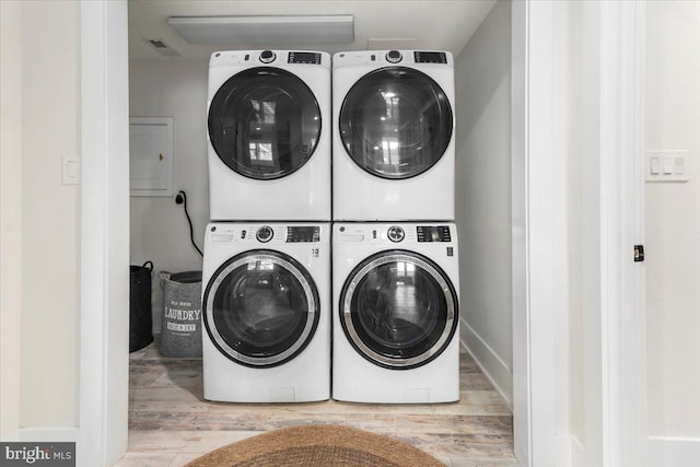 clothes washing area featuring stacked washer and clothes dryer, wood finished floors, and laundry area