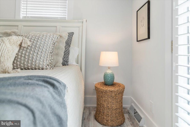 bedroom with wood finished floors, baseboards, multiple windows, and visible vents