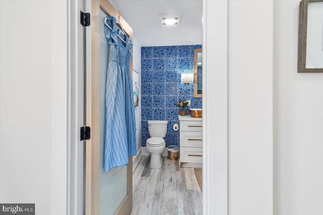 full bath featuring vanity, tile walls, toilet, and wood finished floors
