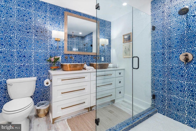 full bathroom with a shower stall, wood finished floors, vanity, and toilet