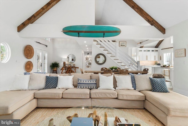 living area with beam ceiling, high vaulted ceiling, and stairway