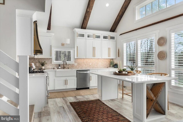 kitchen with light wood-style flooring, light countertops, beam ceiling, dishwasher, and a sink