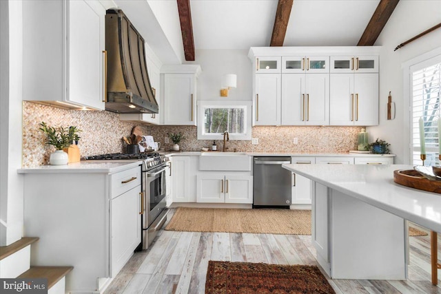 kitchen with a sink, light wood-style flooring, appliances with stainless steel finishes, and white cabinetry