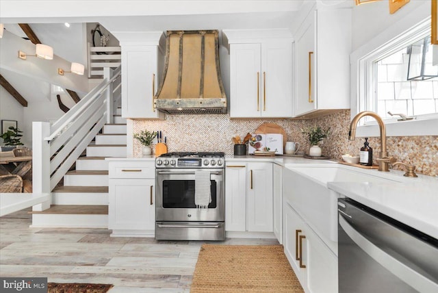 kitchen featuring premium range hood, decorative backsplash, white cabinets, and stainless steel appliances