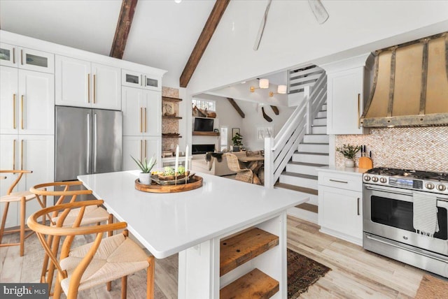 kitchen with glass insert cabinets, a center island, white cabinets, appliances with stainless steel finishes, and vaulted ceiling with beams