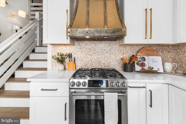 kitchen featuring premium range hood, stainless steel gas range, light countertops, and white cabinetry