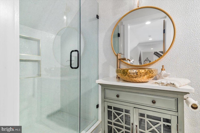 bathroom featuring a textured wall, vanity, and a stall shower
