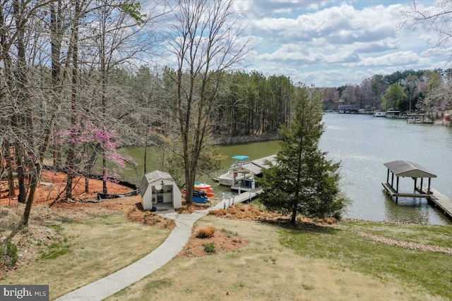 view of dock featuring a water view, a lawn, and boat lift