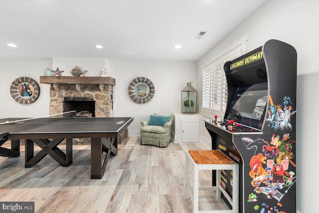 recreation room with wood finished floors, a stone fireplace, visible vents, and recessed lighting