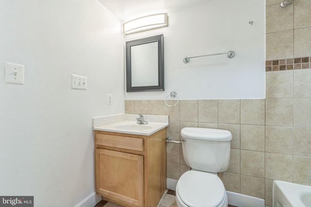 bathroom with a bath, toilet, vanity, and tile walls