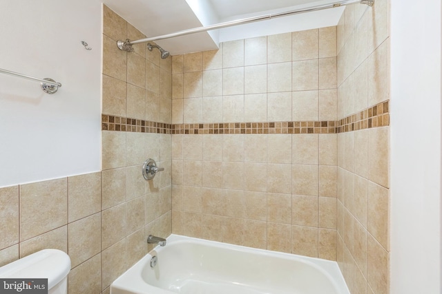 bathroom with tile walls, toilet, and bathtub / shower combination