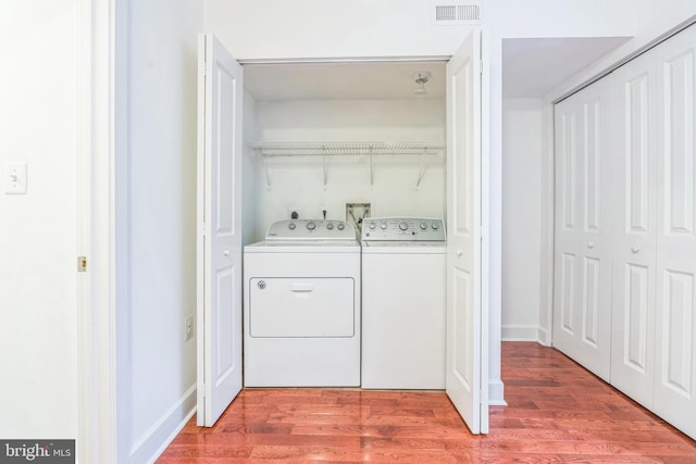 laundry room with washing machine and dryer, visible vents, laundry area, and light wood-type flooring