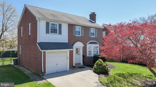 colonial house featuring a chimney, fence, concrete driveway, an attached garage, and brick siding