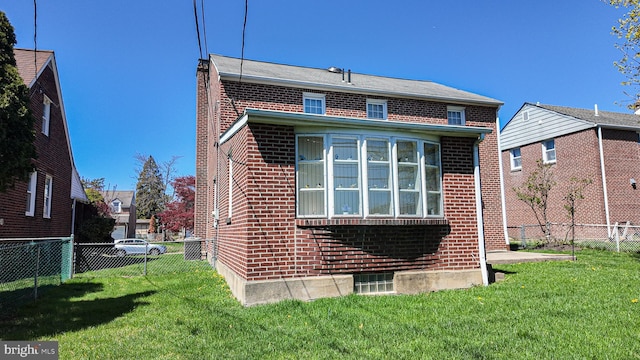 back of house featuring a lawn, a fenced backyard, and brick siding
