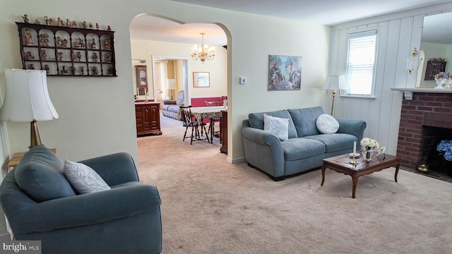 living area featuring a fireplace, carpet flooring, arched walkways, and a chandelier