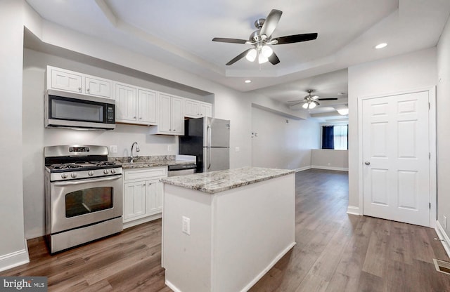 kitchen featuring dark wood-type flooring, white cabinets, recessed lighting, stainless steel appliances, and a raised ceiling