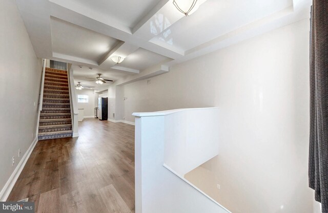 hall featuring baseboards, an upstairs landing, beamed ceiling, wood finished floors, and coffered ceiling