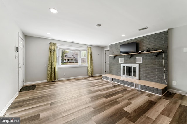 unfurnished living room featuring visible vents, baseboards, wood finished floors, and a fireplace