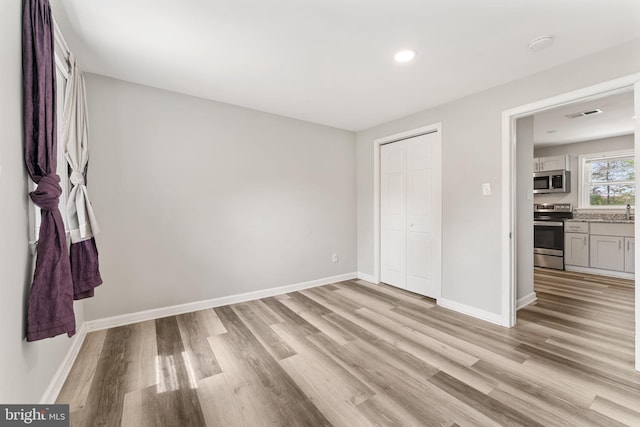 unfurnished bedroom with recessed lighting, a closet, light wood-type flooring, visible vents, and baseboards