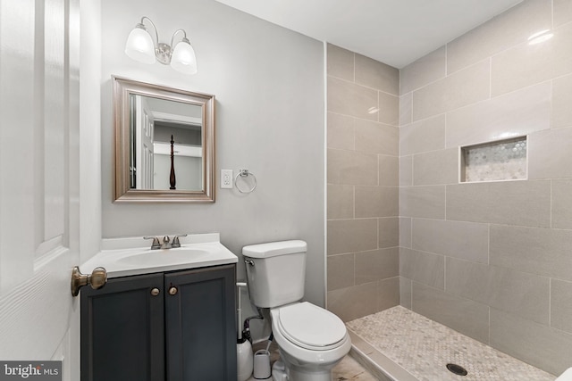 bathroom featuring a tile shower, toilet, and vanity
