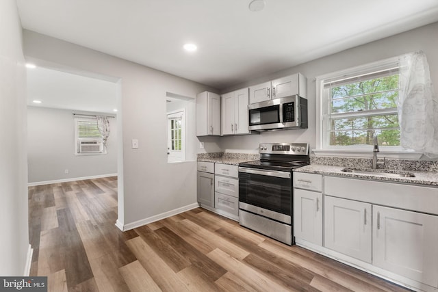 kitchen featuring a healthy amount of sunlight, appliances with stainless steel finishes, light wood finished floors, and a sink