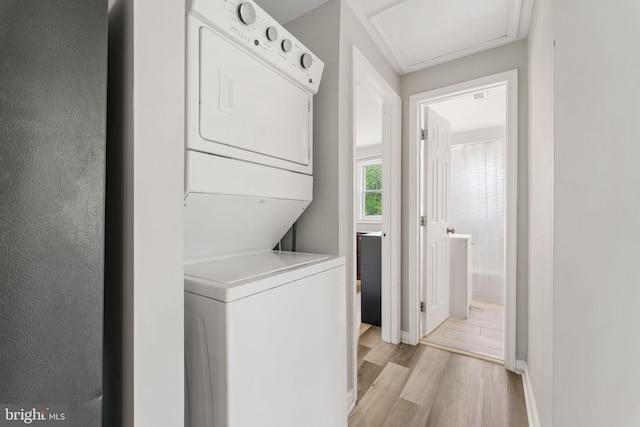 laundry room with stacked washer and dryer, attic access, light wood-style flooring, and laundry area