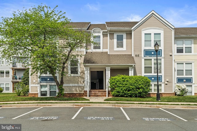 20605 Cornstalk Ter Unit 201, Ashburn, VA 20147 - view of front facade featuring a shingled roof and uncovered parking